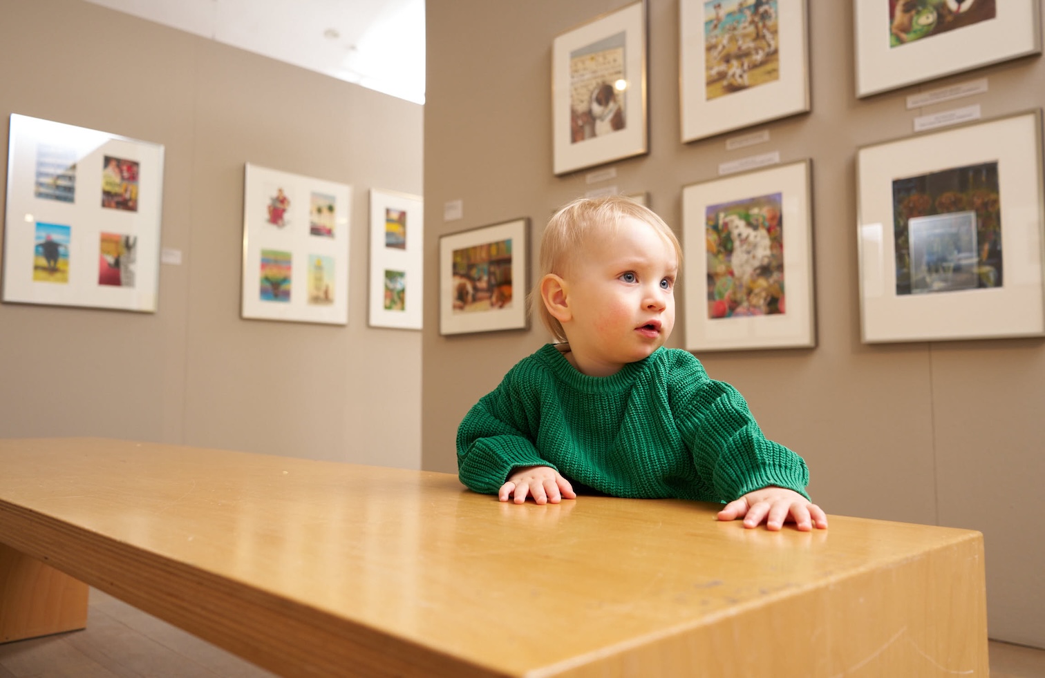 Baby sitz am Tisch. Im Hintergrund Bilder an der Wand
